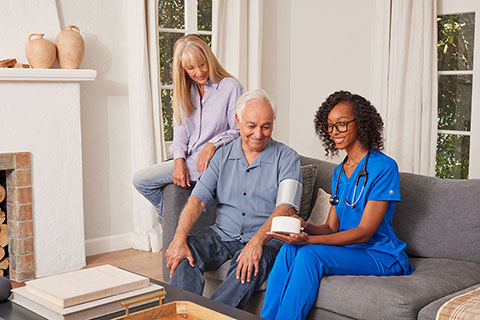 clinical employee checking blood pressure of patient in their living room