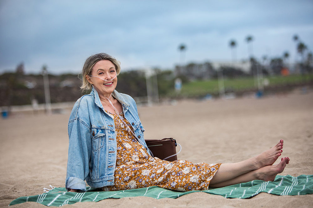 Oxygen White Female Patient POC Sitting on Beach Barefoot Active Lifestyle